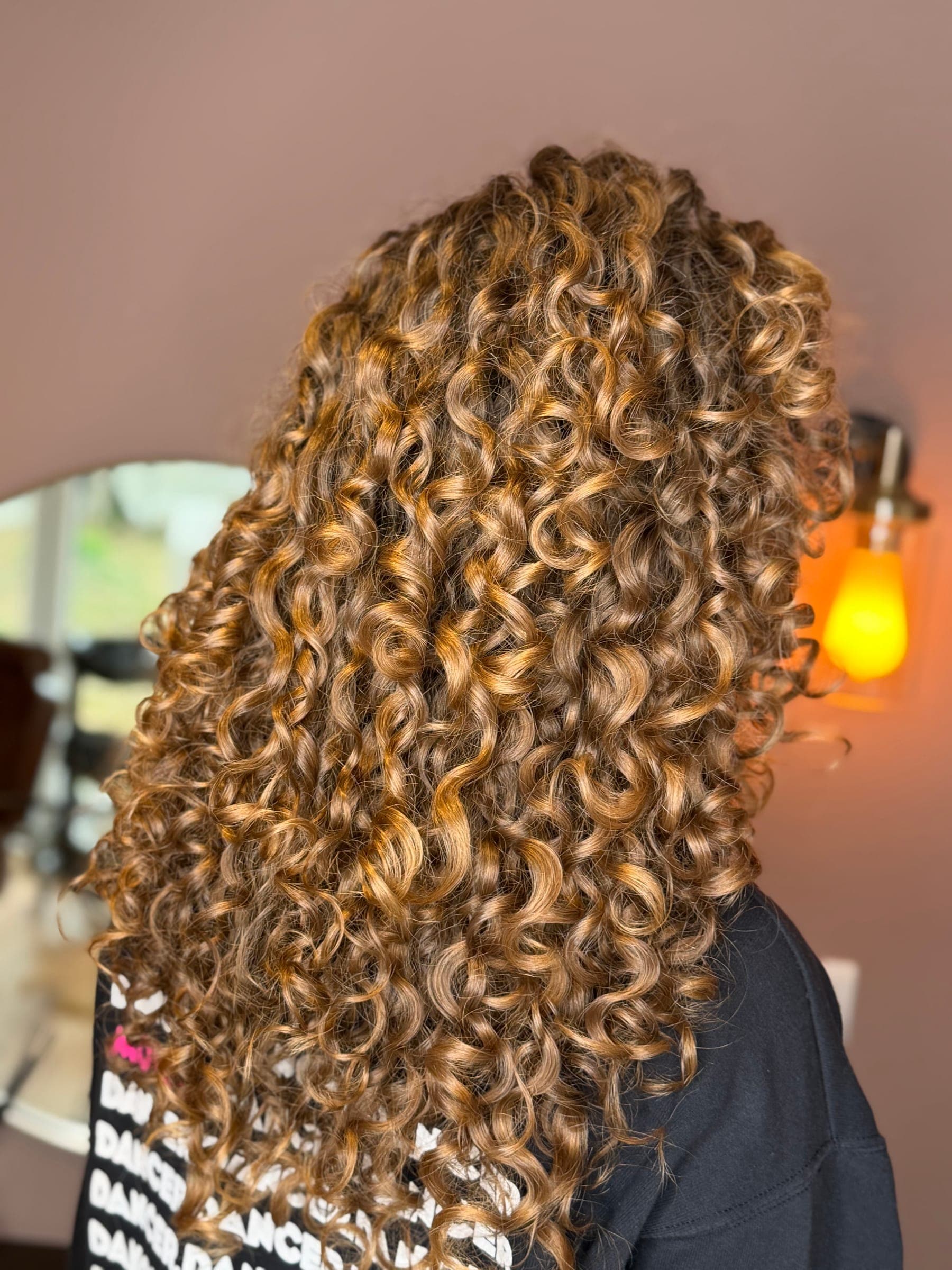 Long golden curls, styled and defined, photographed in the salon